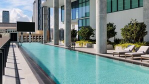 A rooftop pool with clear blue water, surrounded by modern architecture and greenery.