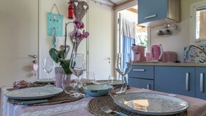 Ein Essbereich mit einem Tisch für zwei Personen, komplett mit Tellern, Gläsern und einer Vase mit Blumen.