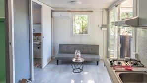 Eine kompakte Küche mit grauem Sofa, einem kleinen runden Tisch mit einem Glas und einem Fenster, das für natürliches Licht sorgt.