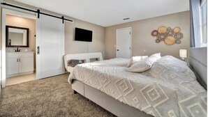 Un dormitorio con una cama, un televisor, una puerta y un adorno en la pared.