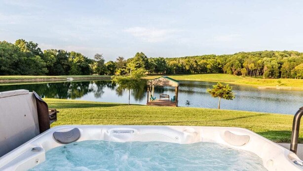 A hot tub with a view of a lake and a gazebo.