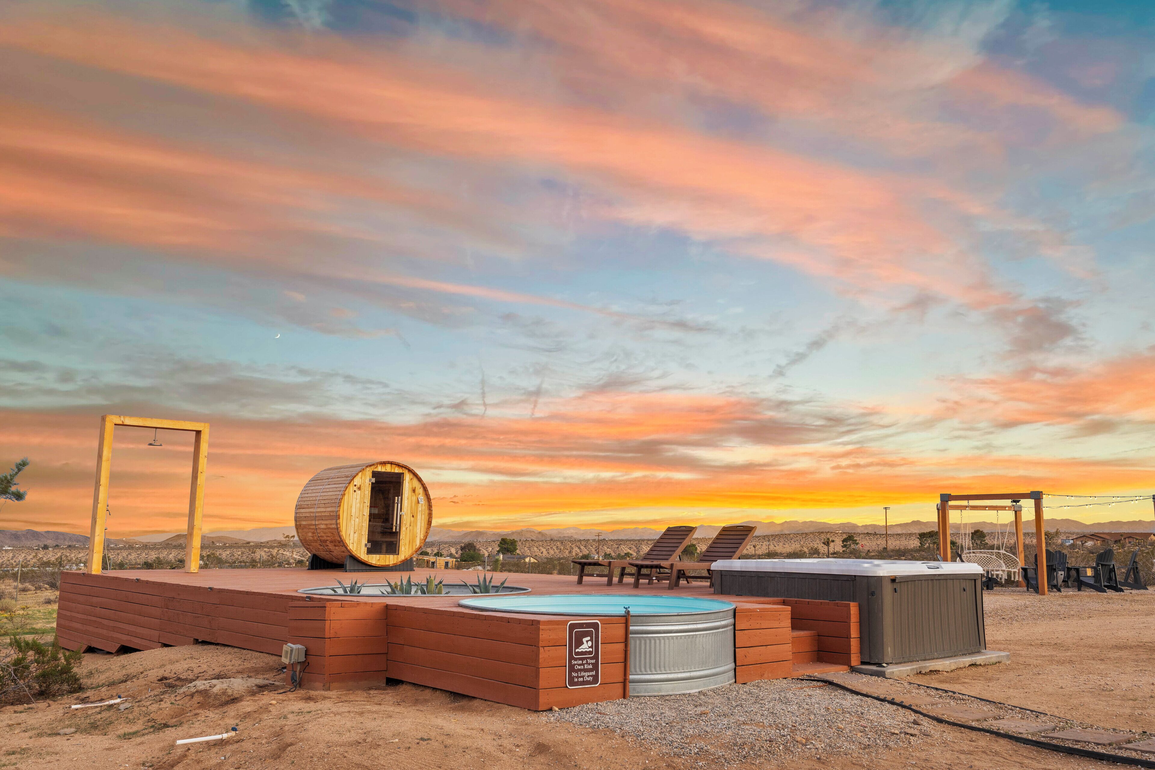 A desert resort with a wooden structure, a circular wooden barrel, and a pool area.