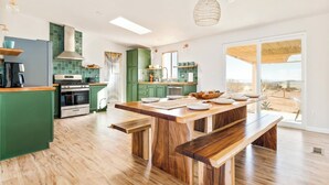 A modern kitchen with green cabinets, a central island, and a large window offering a view of the outdoors. - Joshua Tree-Spa Pool Firepit Sauna Game Room (Yucca Valley)