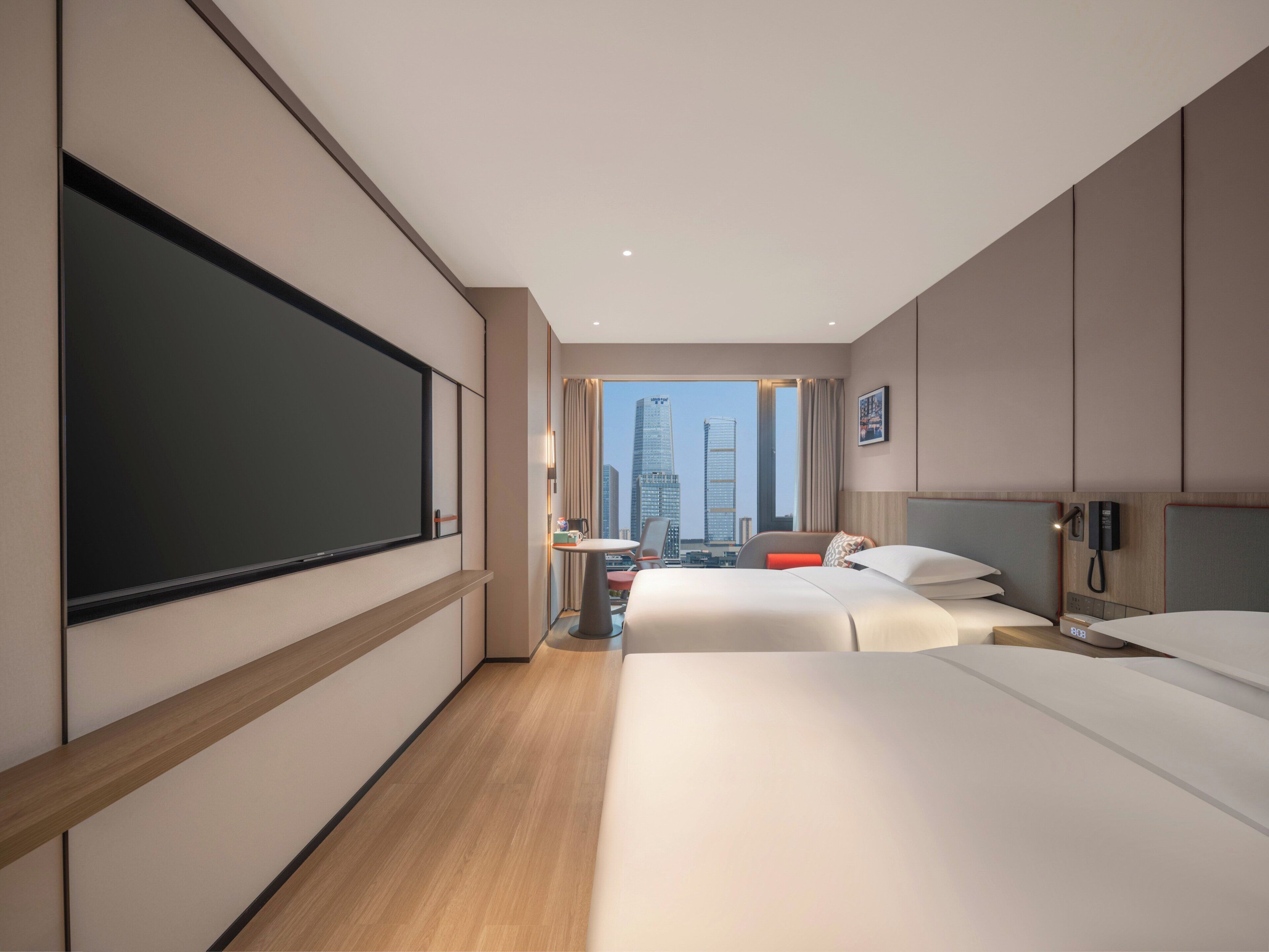 Une chambre d’hôtel avec un grand lit, un bureau, une chaise, une télévision et une vue sur le paysage urbain.