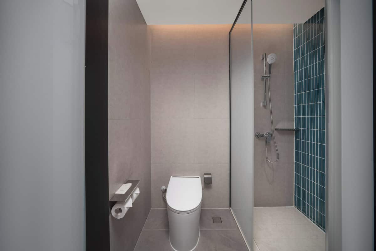 A modern bathroom with a toilet, a shower, and a tiled wall.