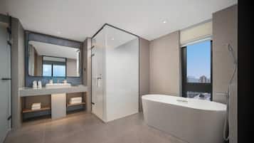 Un baño moderno con una bañera grande, una ducha con mampara de vidrio y un tocador con espejo.
