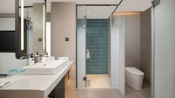 A modern bathroom with a glass shower enclosure, a white sink, and a toilet.