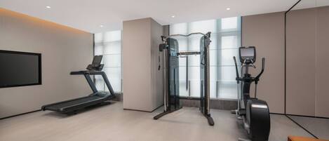 Ein moderner Fitnessraum mit Laufband, Crosstrainer und Kraftmaschine.