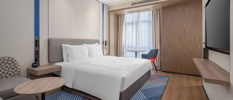Une chambre d’hôtel moderne équipée d’un grand lit, d’un bureau, d’une chaise et d’un téléviseur.