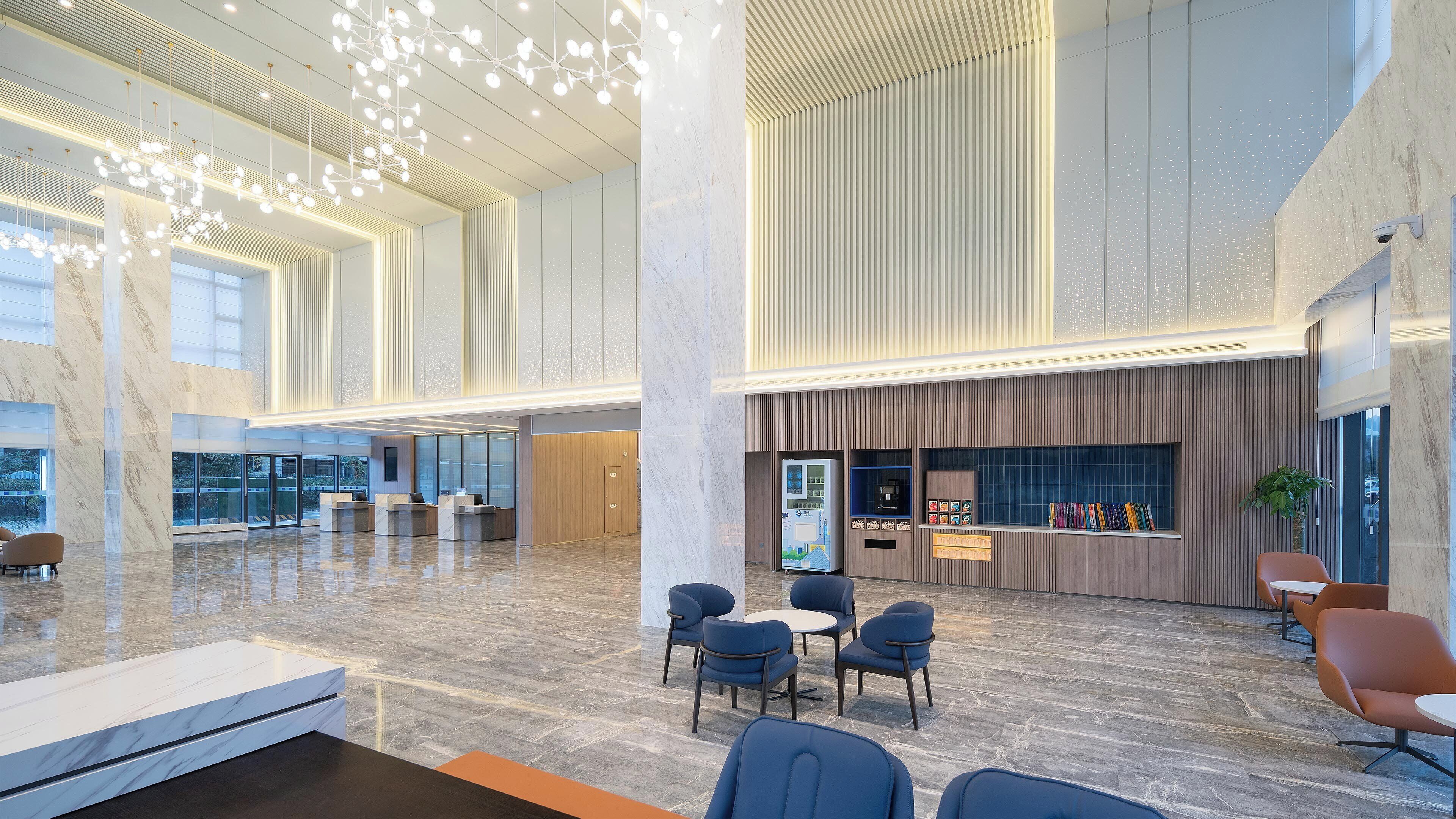 A spacious lobby with marble flooring, modern seating, and a vending machine.