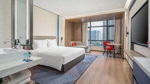 A modern hotel room with a large bed, a desk, a chair, a TV, and a window with a city view. - Holiday Inn Express Chenzhou Suxian by IHG (Chenzhou)