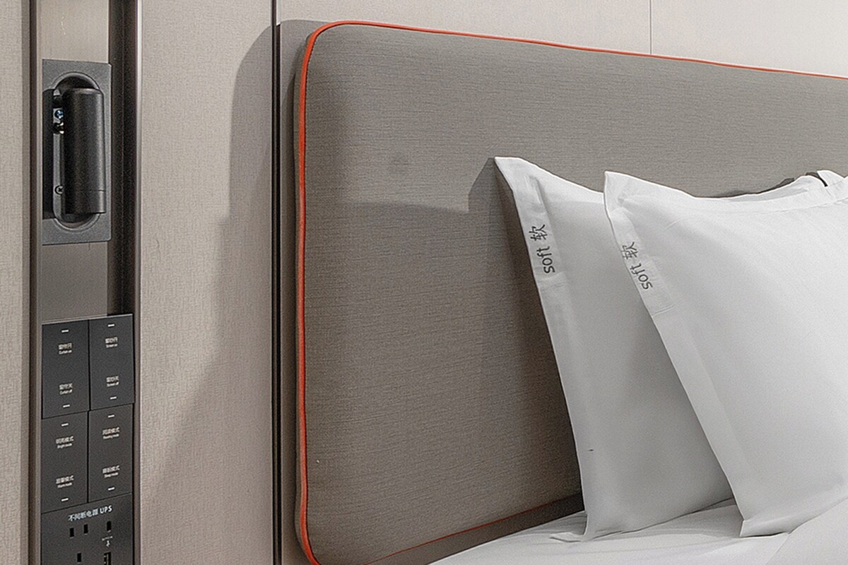 Ein Hotelzimmer mit Bett, Bedienfeld und Kissen mit Aufdruck.