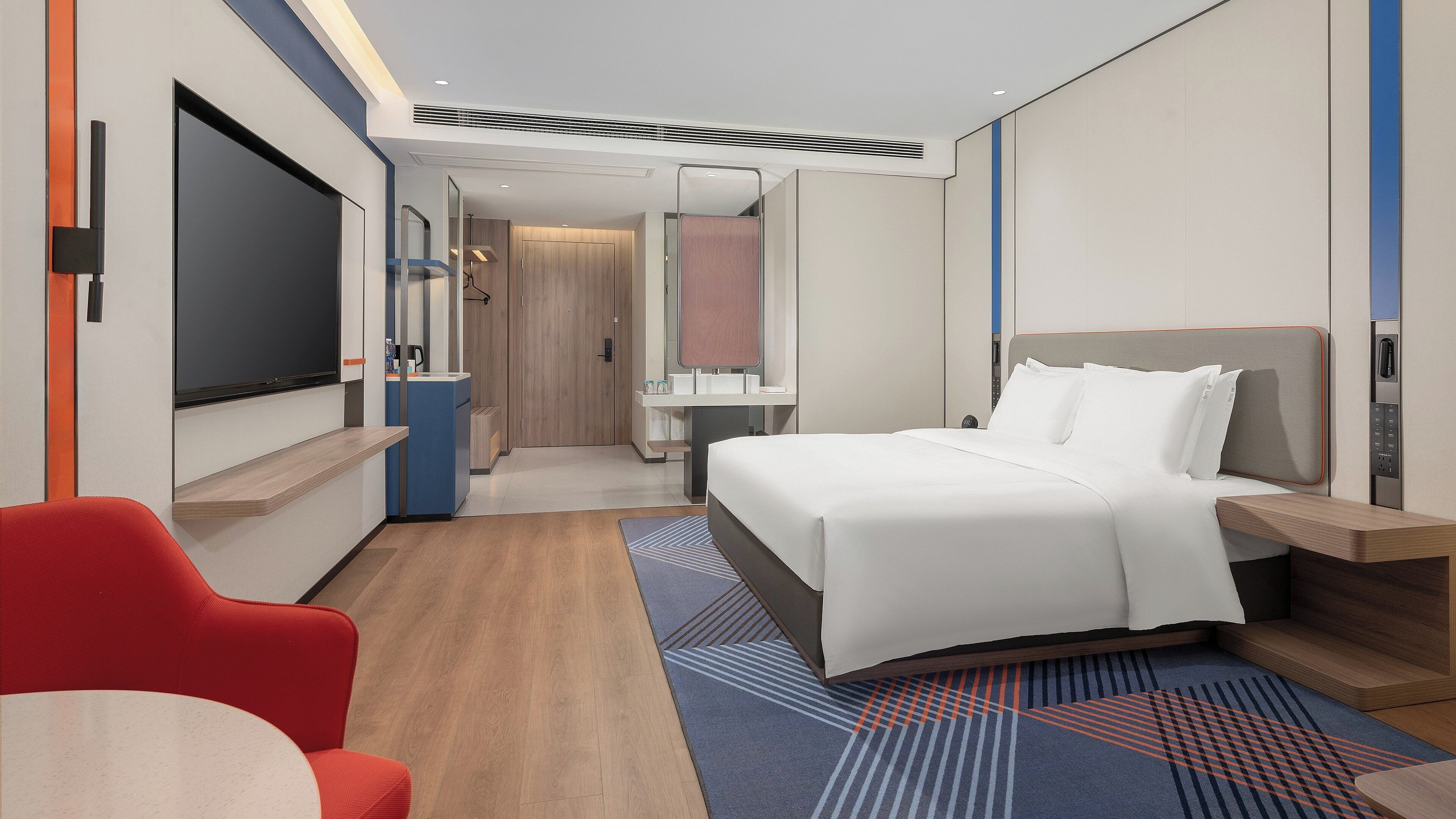 Une chambre d’hôtel moderne équipée d’un grand lit, d’un bureau, d’une chaise et d’un téléviseur.