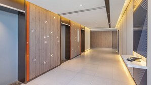 A modern hallway with wooden paneling, a white reception desk, and a digital information board. - Holiday Inn Express Chenzhou Suxian by IHG (Chenzhou)