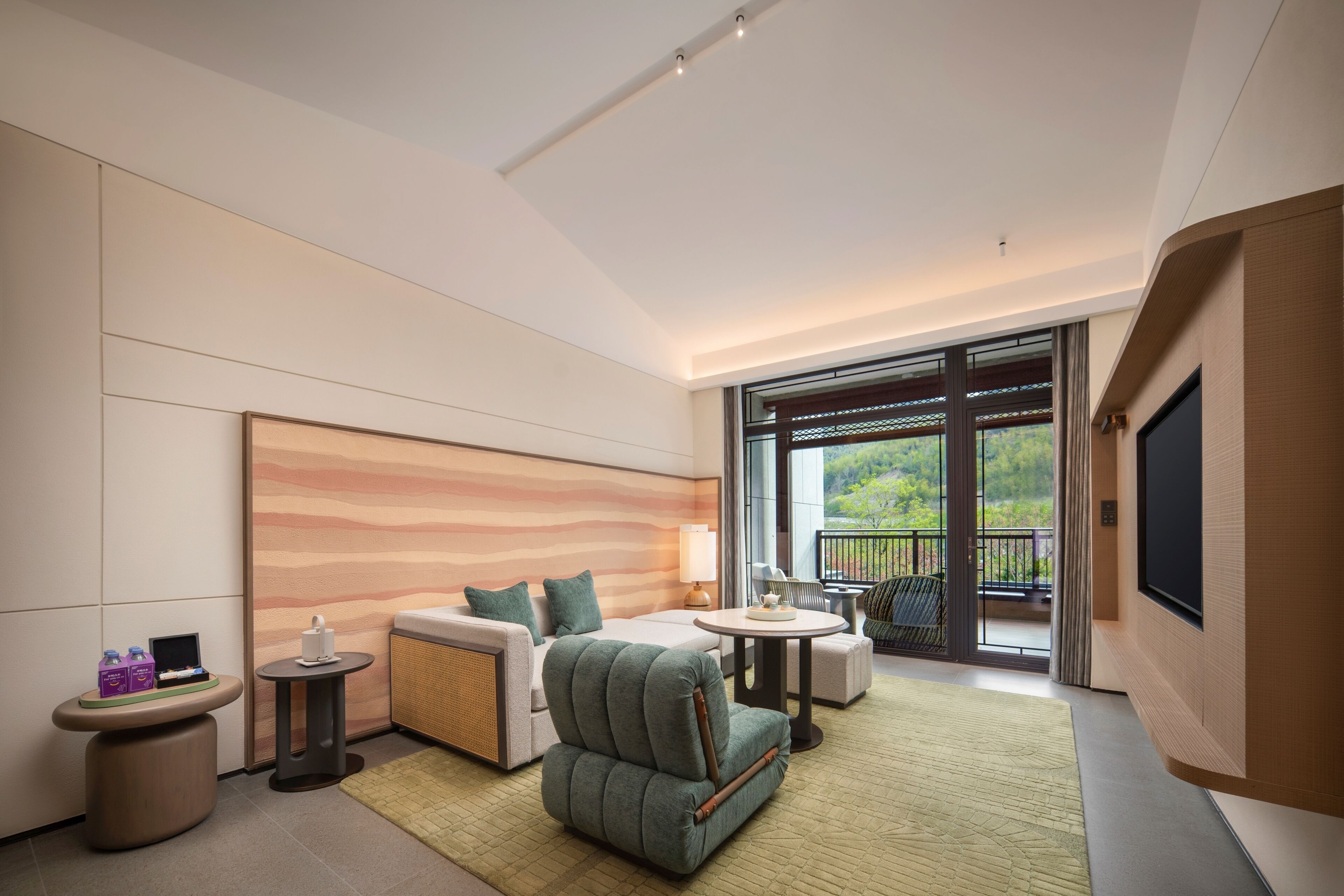 Ein modernes Hotelzimmer mit Bett, Sitzgelegenheit, Fernseher und einem Balkon mit Blick.
