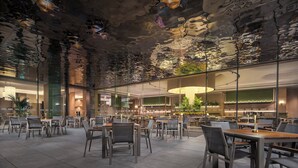 Un restaurante moderno con un diseño de techo original, separaciones de vidrio y mobiliario contemporáneo.
