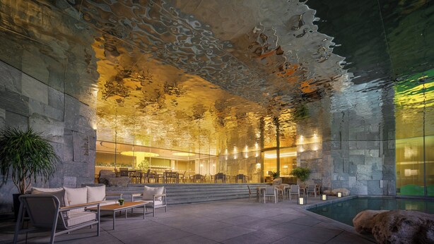 Un espacio interior moderno con una pared de piedra, zona de estar y piscina.