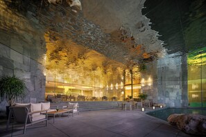 A modern indoor space with a stone wall, seating area, and a pool. - Holiday Inn Resort Ningbo Ninghai by IHG (Ningbo)