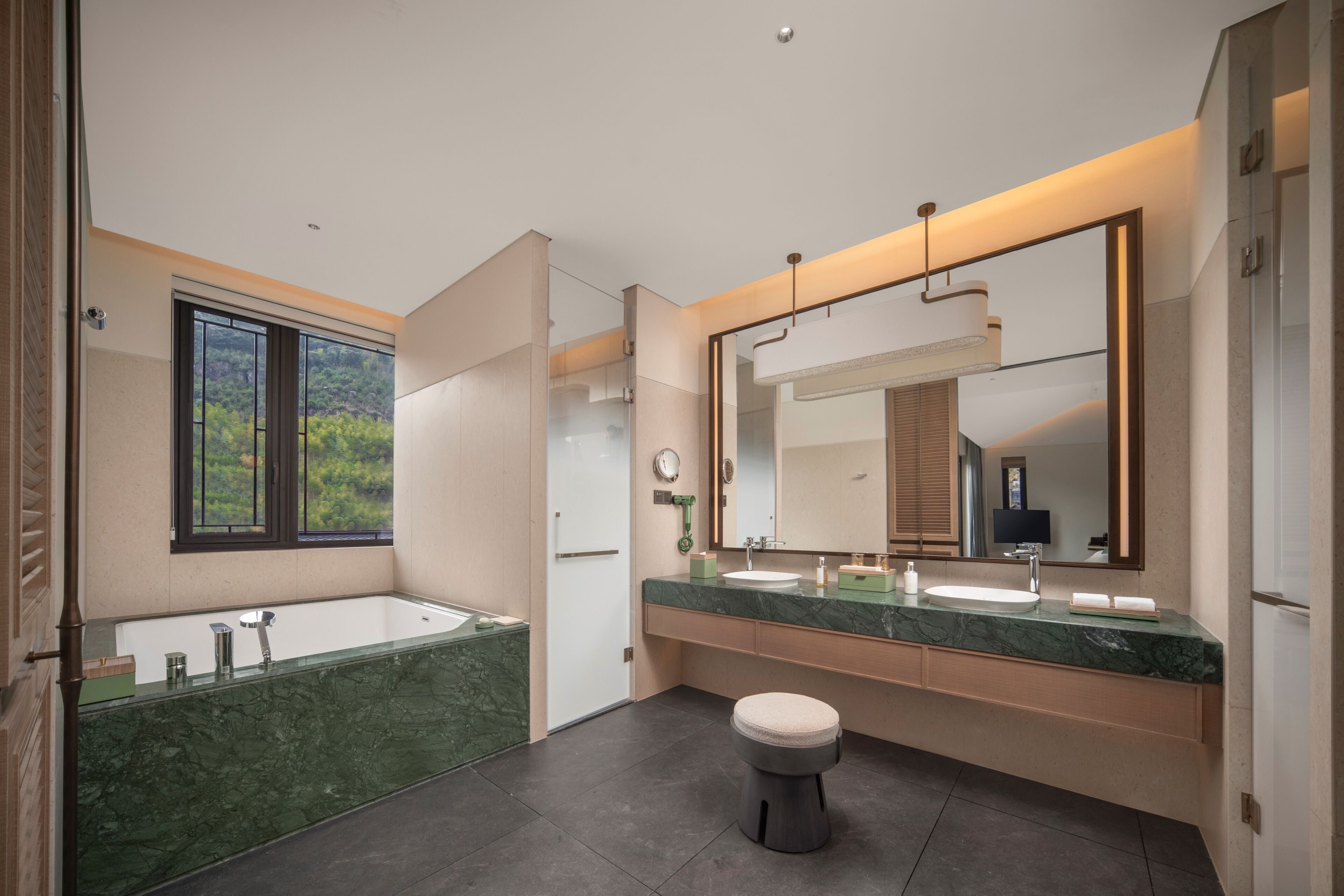 Ein modernes Badezimmer mit einer großen Badewanne, zwei Waschbecken, einer Toilette und einem großen Spiegel.