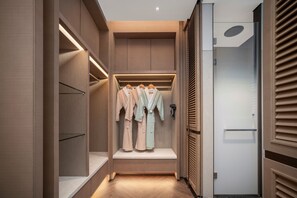 Ein modernes Interieur mit begehbarem Kleiderschrank, integrierten Regalen und einer eingelassenen Deckenleuchte.