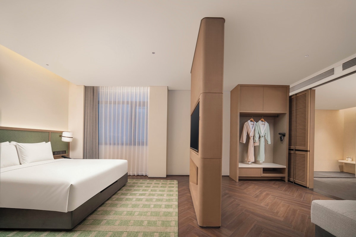 Une chambre d’hôtel comprenant un lit, une télévision, une armoire et un coin salon.