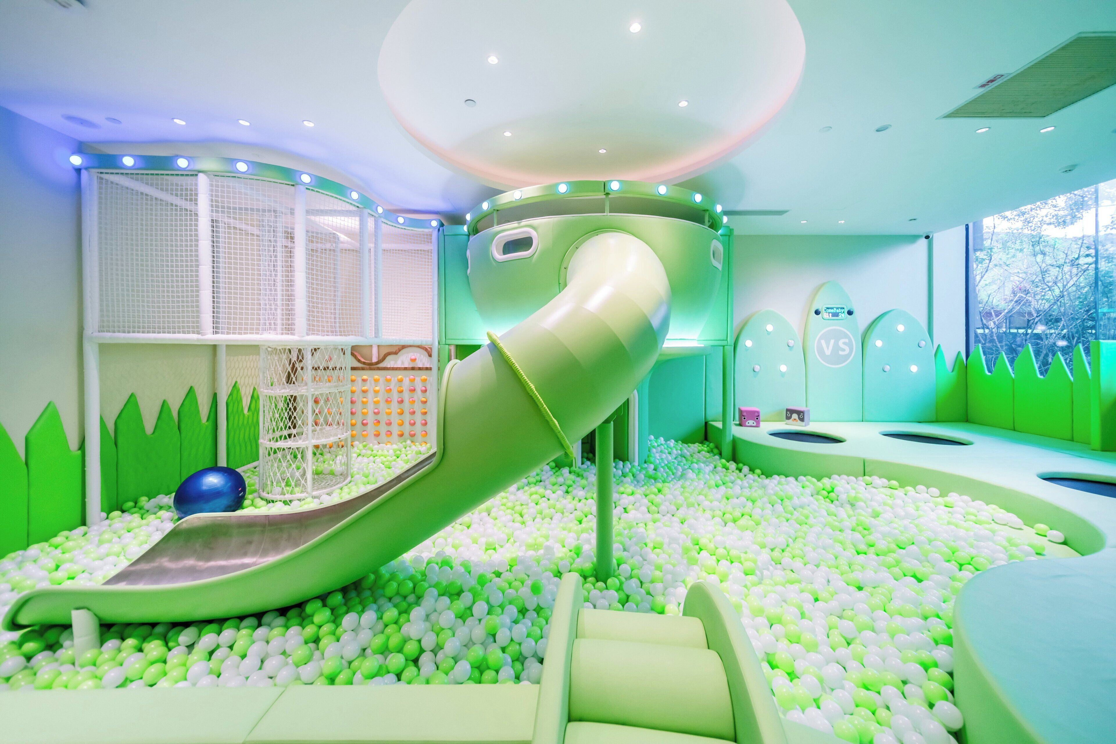 A children's play area with a slide, ball pit, and netted climbing area.