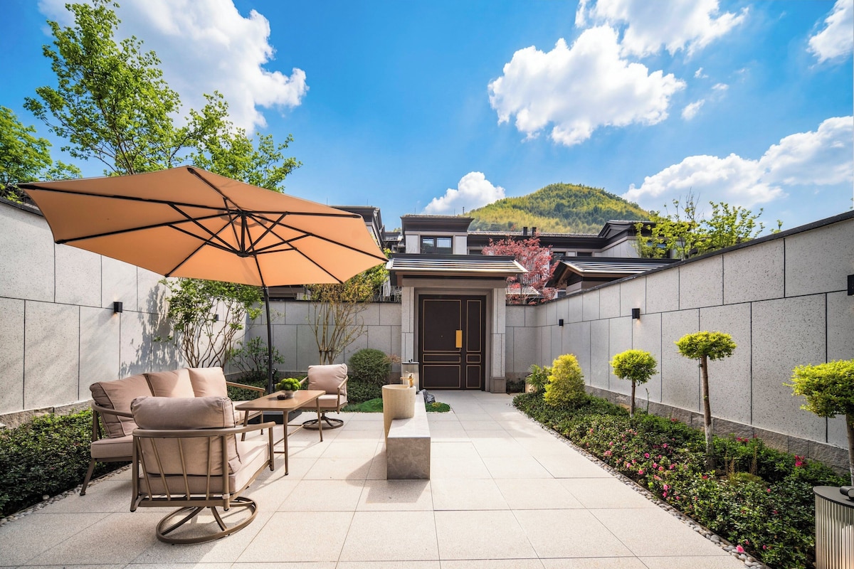 Une terrasse avec des meubles d’extérieur, un grand parasol et une vue sur une montagne.