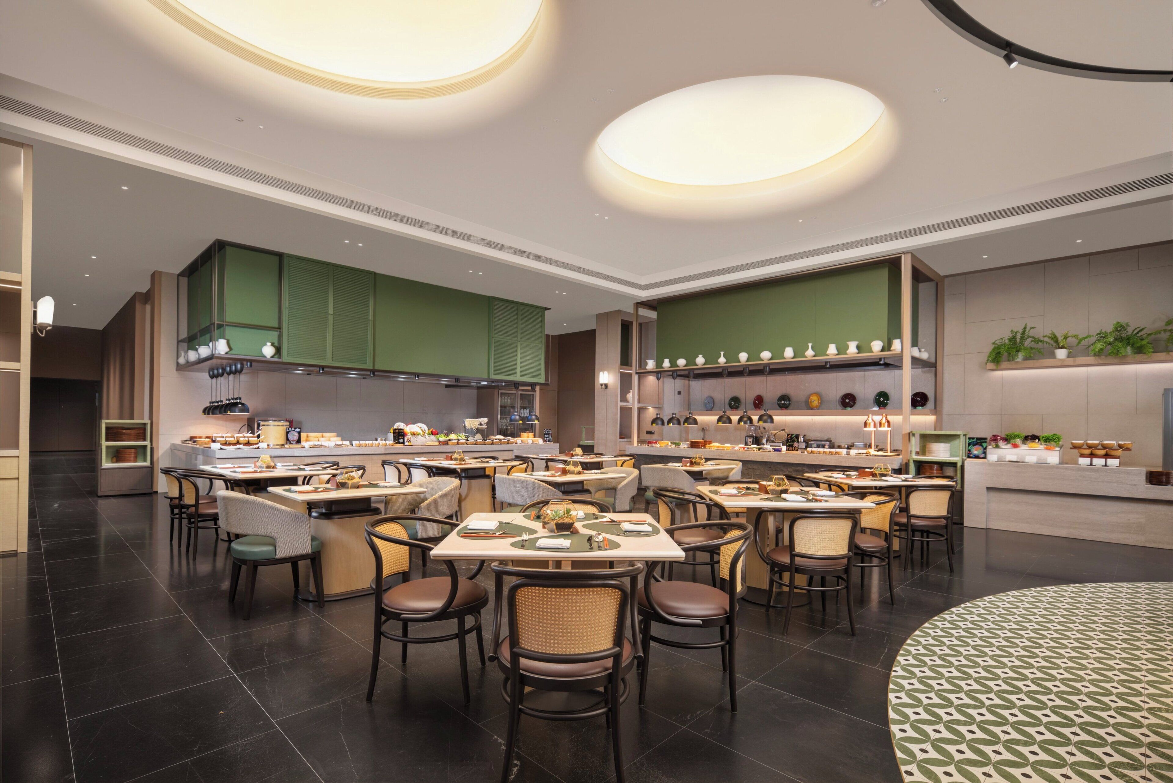 A modern restaurant with multiple dining tables and chairs, a kitchen area, and a reception desk.