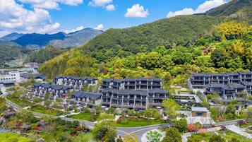Un barrio residencial con edificios de apartamentos modernos, una carretera sinuosa y colinas verdes exuberantes al fondo.