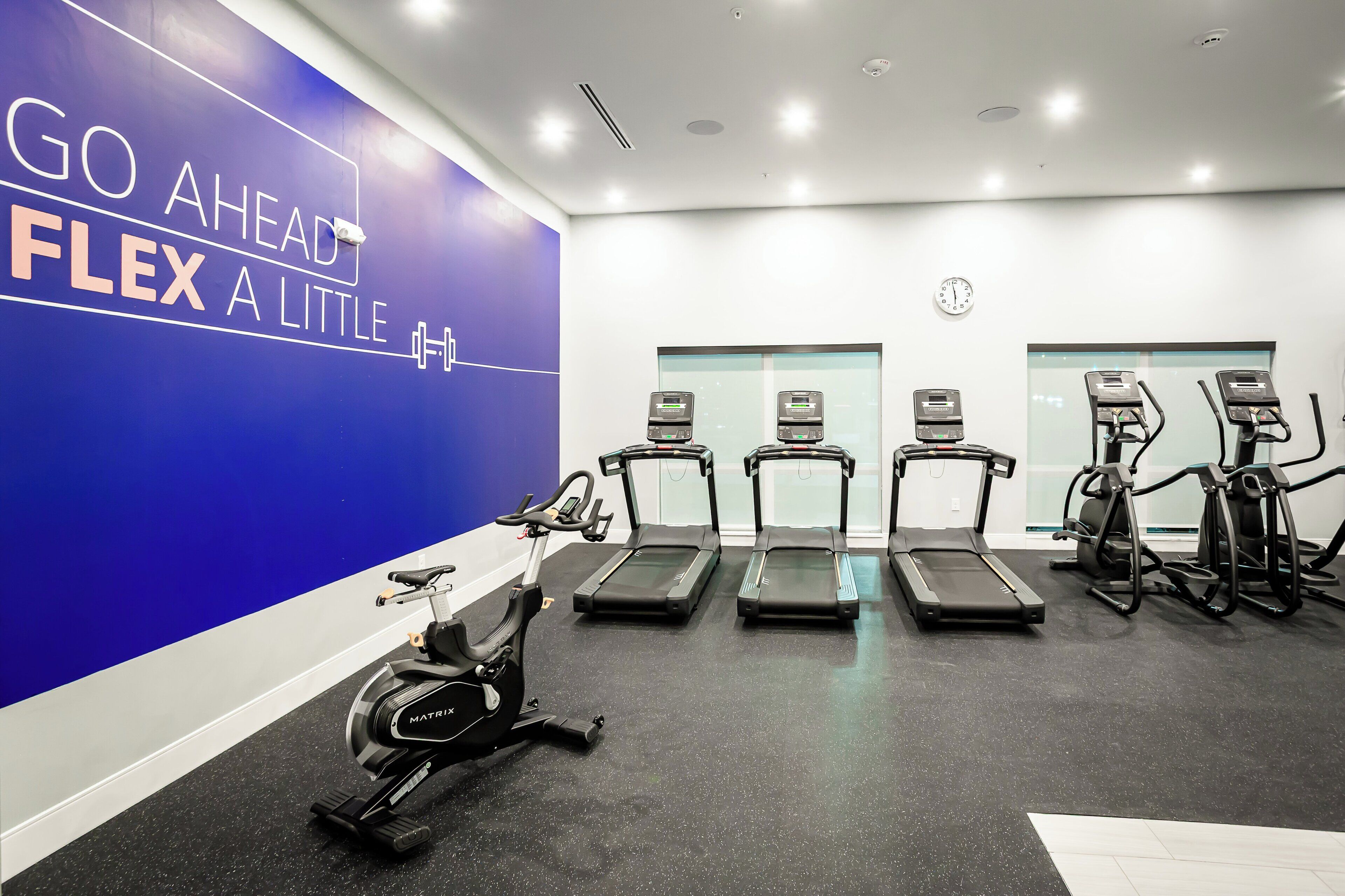 A gym with treadmills, an elliptical, and a wall with motivational text.