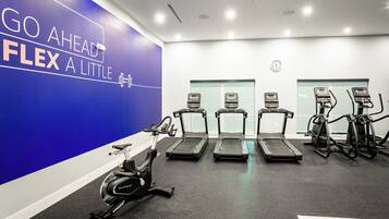 A gym with treadmills, an elliptical, and a wall with motivational text.