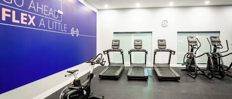 A gym with treadmills, an elliptical, and a wall with motivational text.