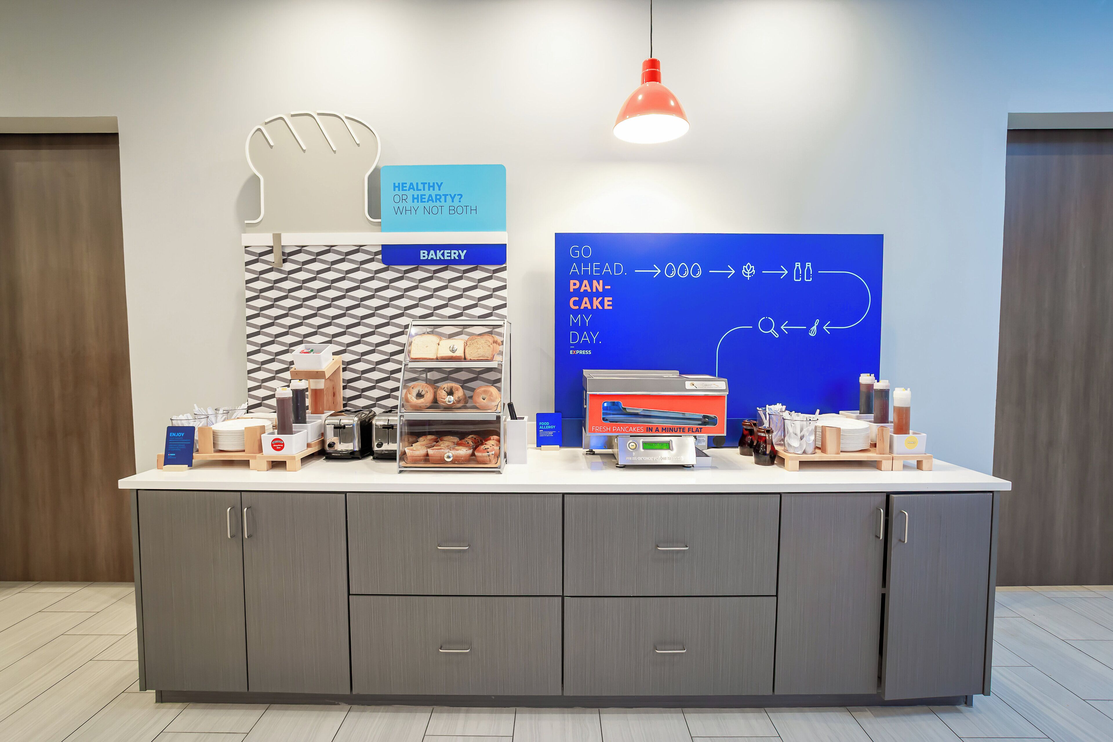 A bakery counter with a sign reading "BAKERY" and a sign above it stating "HEALTHY OR HEARTY? WHY NOT BOTH".