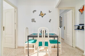 Een eethoek met een tafel, stoelen, een wand met vlinderstickers en een deur.