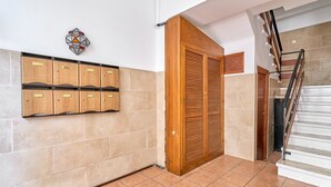 A hallway with a tiled floor, a wooden door, a wall-mounted storage unit, and a staircase. - Apartment 'Butterfly' with Private Terrace, Wi-Fi and Air Conditioning (Nerja)