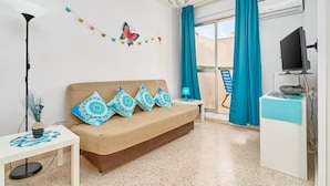 A room with a sofa, a TV, a desk, a lamp, and a window with curtains. - Apartment 'Butterfly' with Private Terrace, Wi-Fi and Air Conditioning (Nerja)