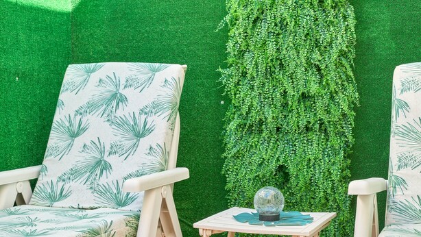 Two white chairs with palm leaf patterns, a small wooden table with a globe and a blue object, and a green wall with dense foliage. - Apartment 'Naranja' with Private Terrace, Wi-Fi and Air Conditioning (Nerja)
