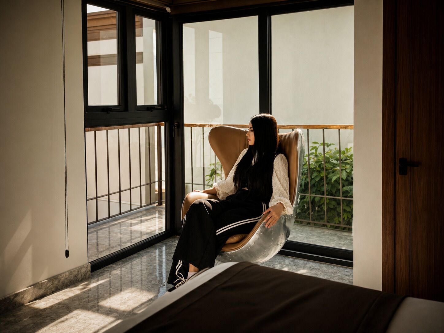 Una habitación con un ventanal grande, una cama y una silla.