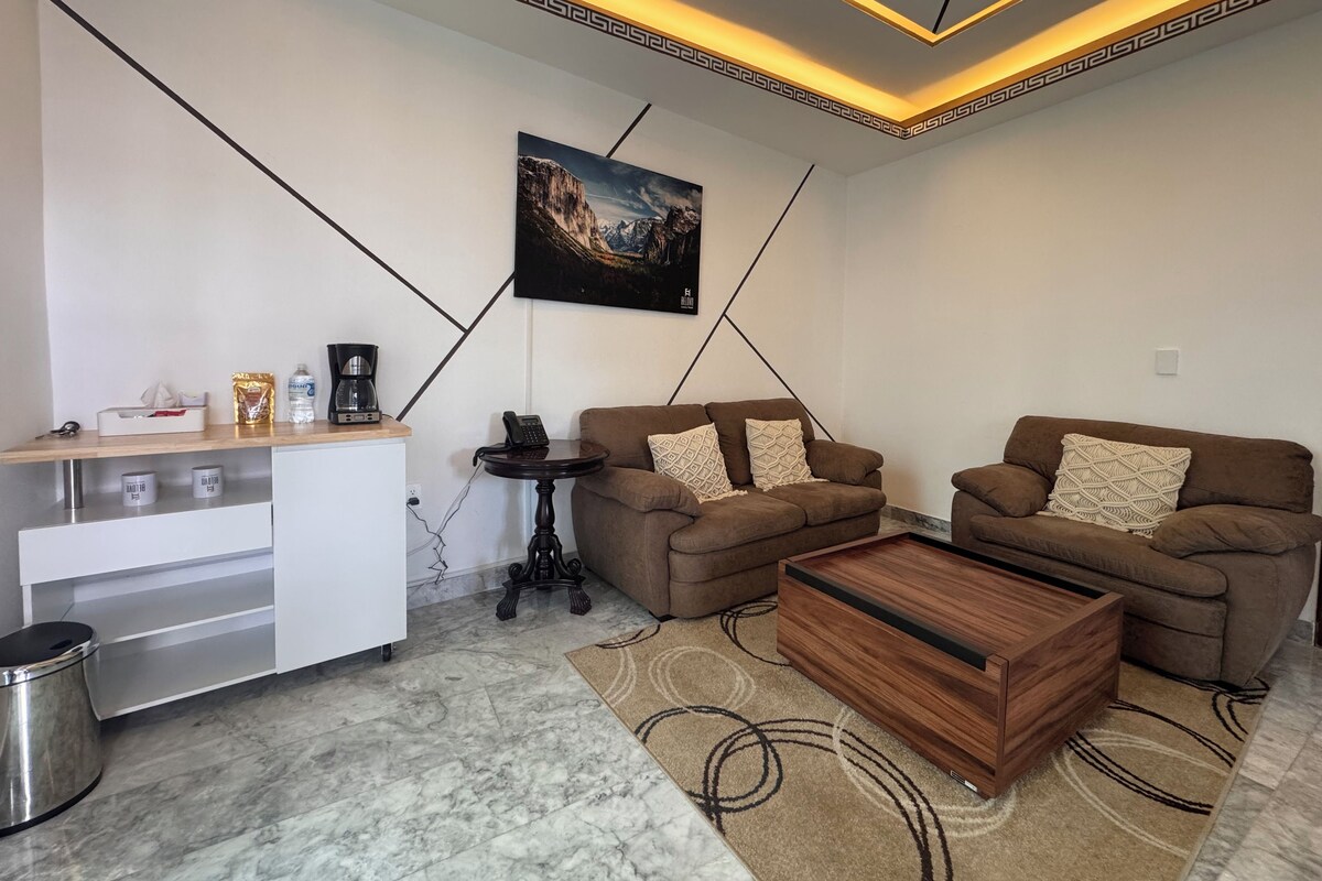 A modern living room with two sofas, a coffee table, a small table with a phone, and a painting on the wall.