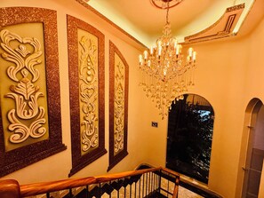 A staircase with a wooden handrail, a chandelier, and decorative wall panels. - Belova Luxury Hotel, San Cristobal de las Casas (San Cristóbal de las Casas)