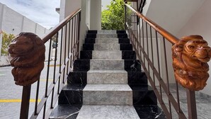 Una escalera con escalones de mármol y barandilla de madera, que conduce a un arco de entrada.