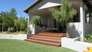 A modern house with a covered porch, wooden steps, and lush greenery.