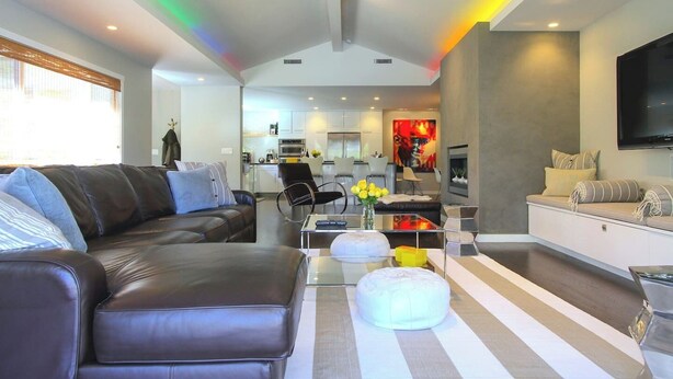 A modern living room with a sofa, ottoman, and a flat-screen TV.