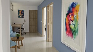 A modern living room with a blue wall, a large framed painting of a lion, a wooden cabinet, and a small table with a plant.