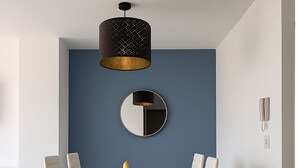 A dining area with a rectangular table, six chairs, a round mirror, and two pendant lights.