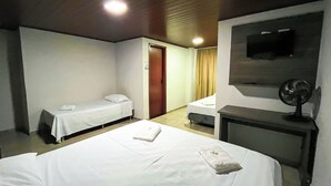 A hotel room with two single beds, a desk, a chair, a TV, and a ceiling fan. - Hotel ROF (Telemaco Borba)
