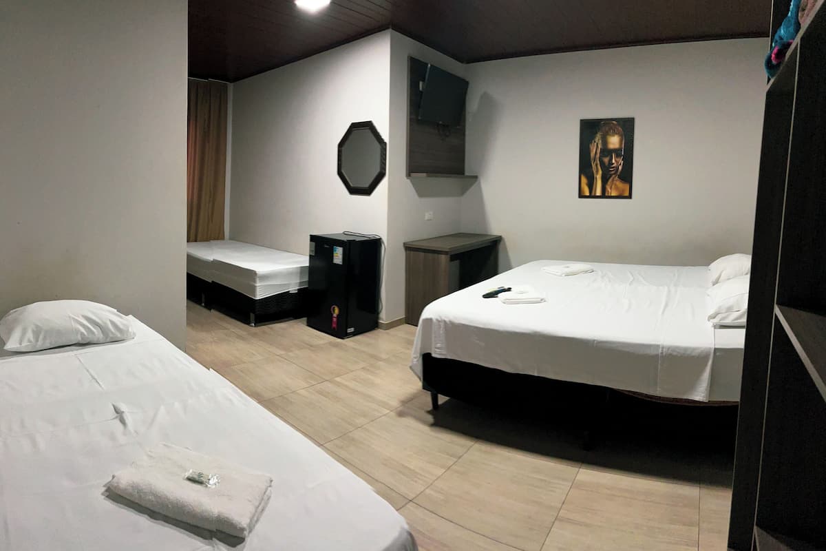 A hotel room with two single beds, a desk, a mirror, and a painting on the wall.