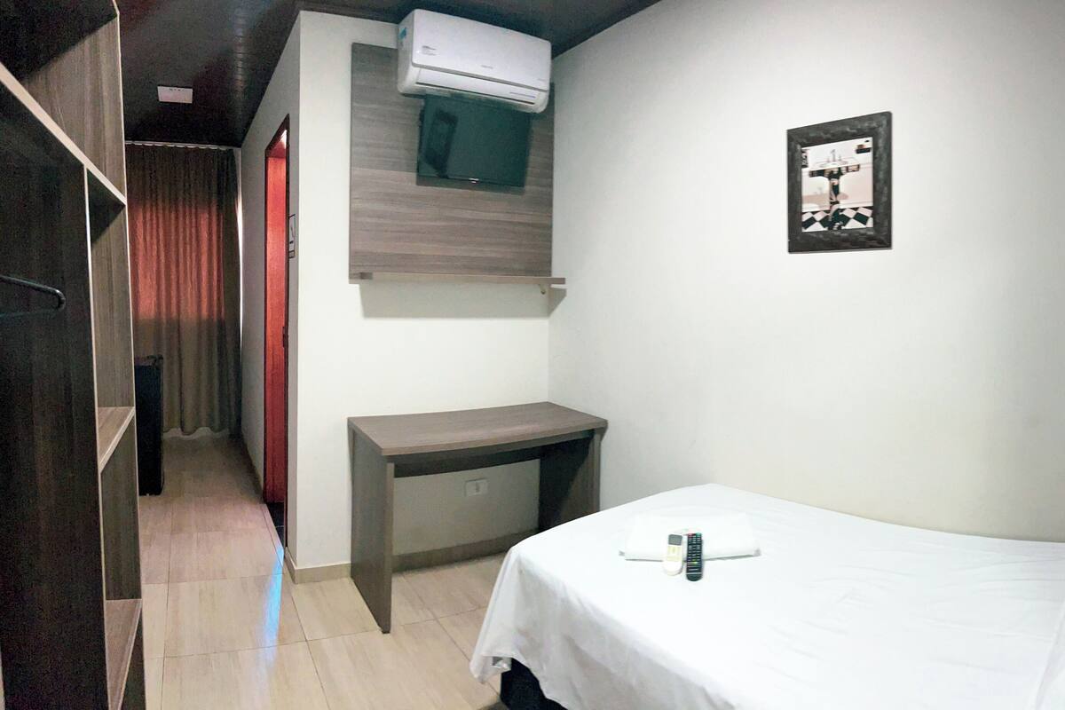 A small, compact room with a single bed, a desk, and a wardrobe.