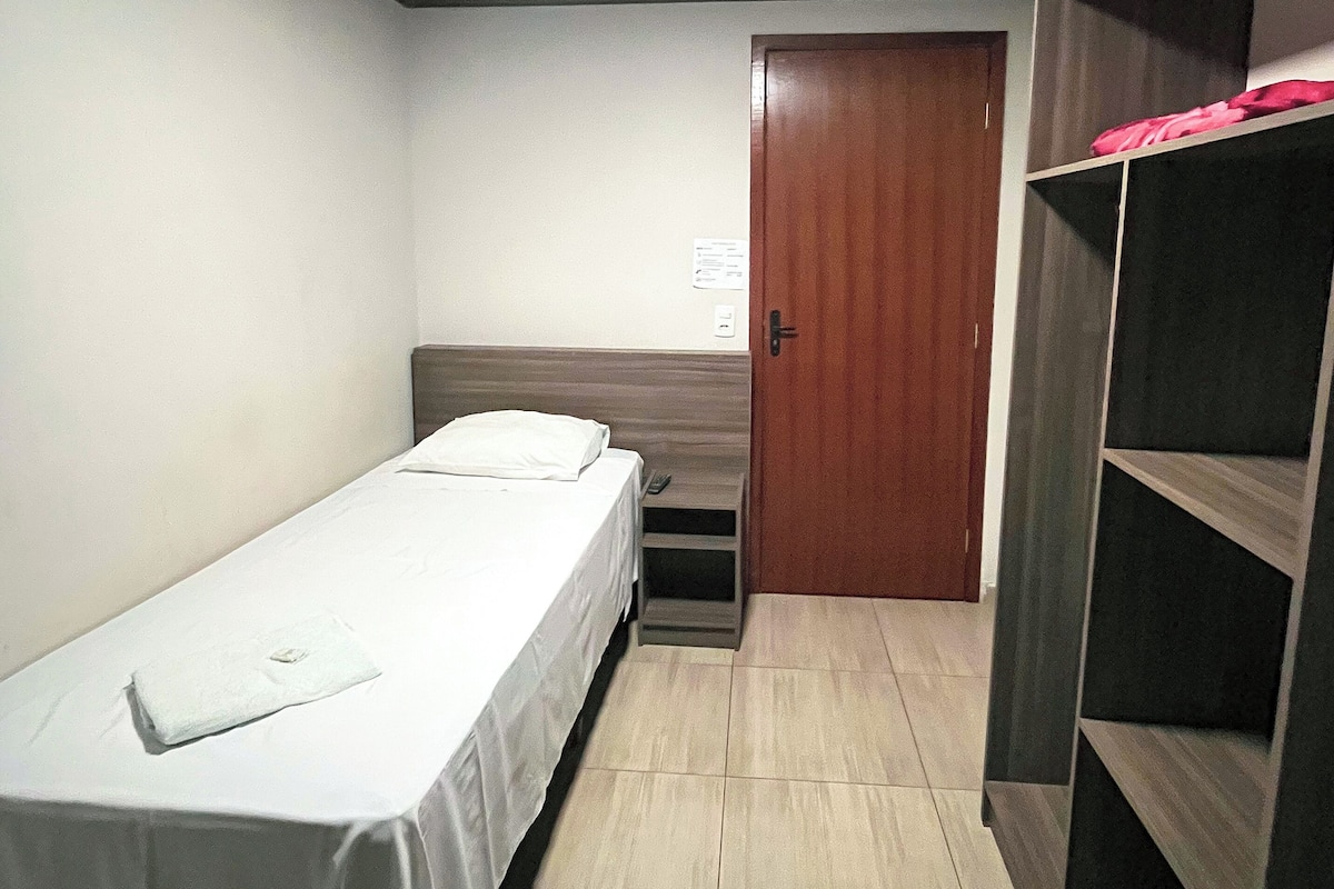 A small, single-bed room with a wooden door and a small desk.