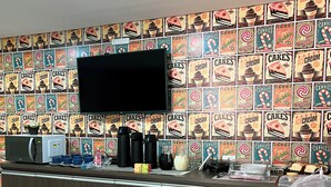 A kitchen area with a microwave, coffee maker, and a flat-screen TV mounted on the wall. - Hotel ROF (Telemaco Borba)